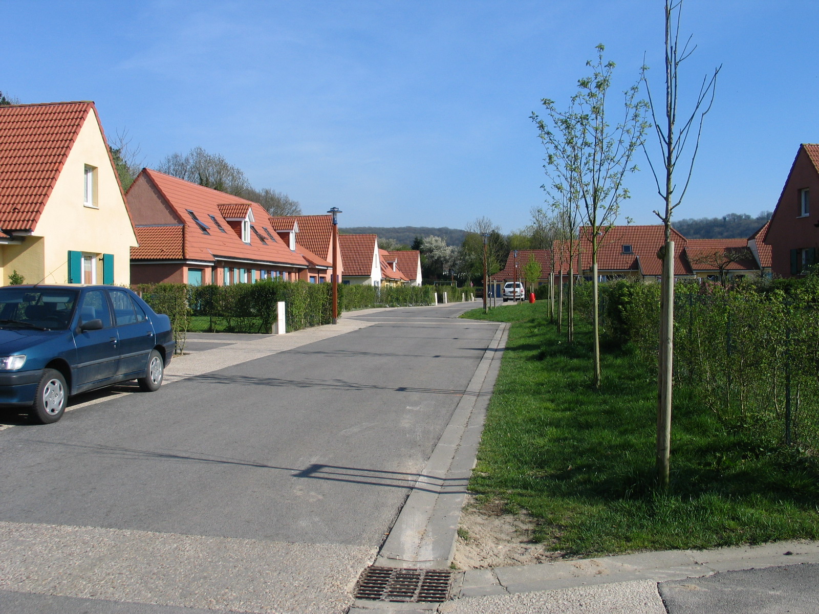Rue résidentielle d'un lotissement à Longfossé, avec maisons individuelles, trottoir et arbres plantés