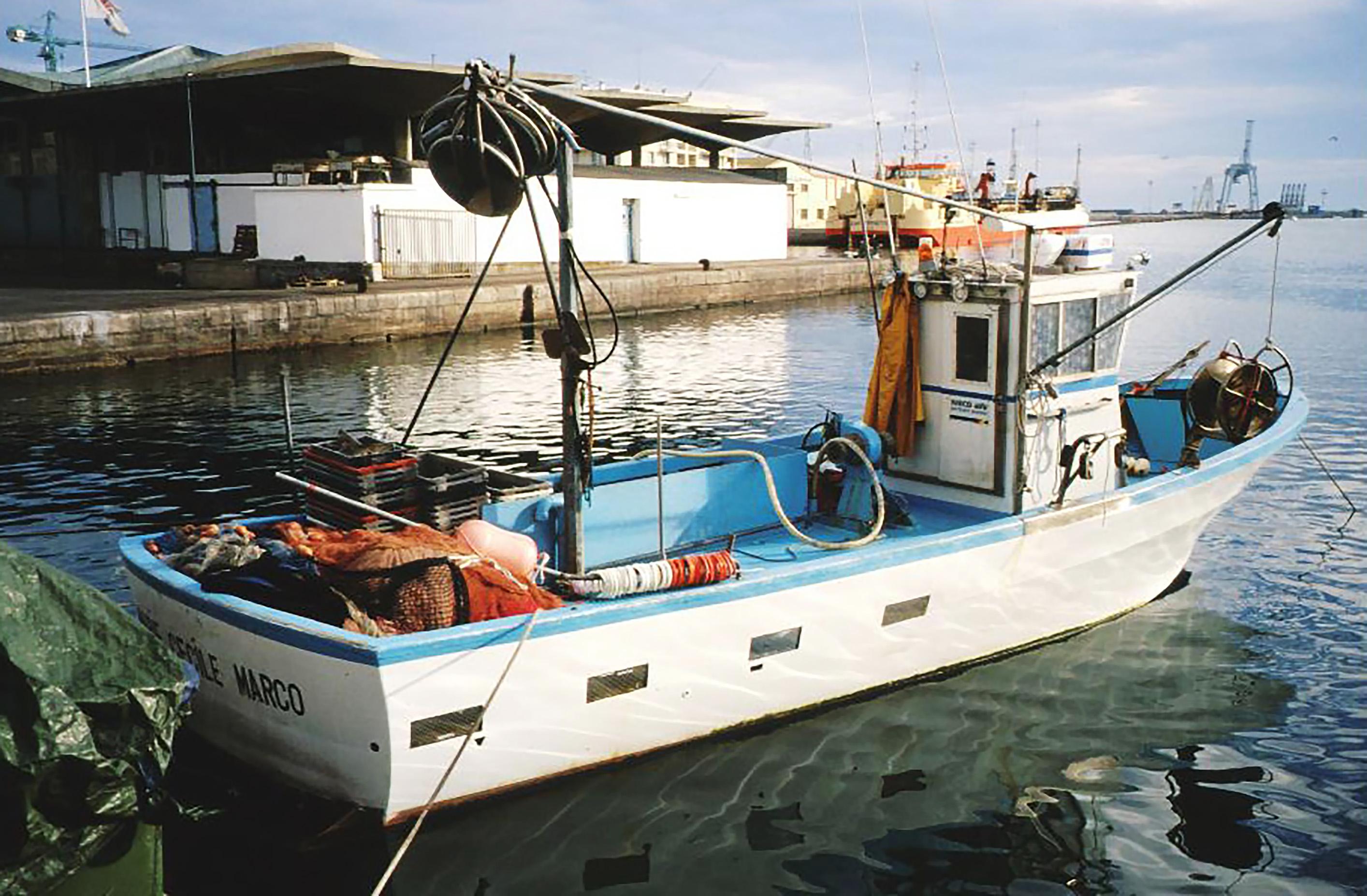 Petit navire de pêche méditerranéen équipé de filets dans un port